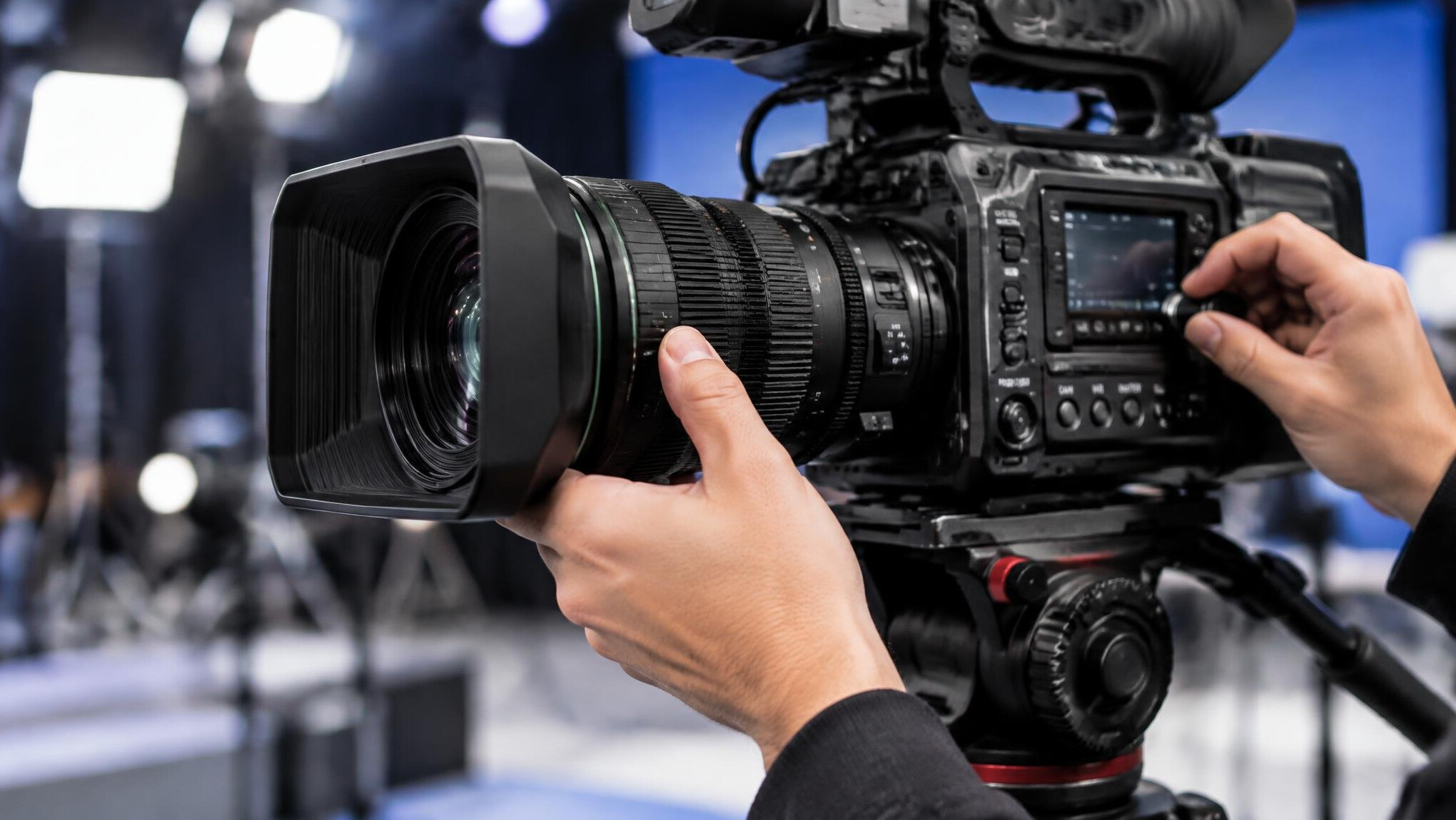 Hands adjusting a professional broadcast camera